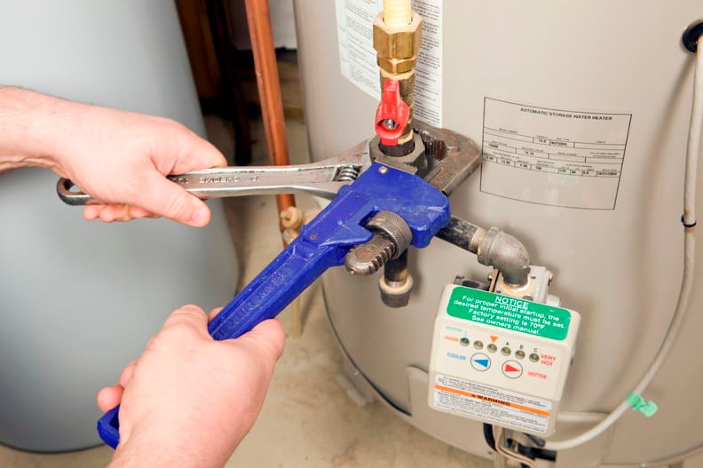 Plumber repairing water heater pipe connection in Dunedin, Florida home