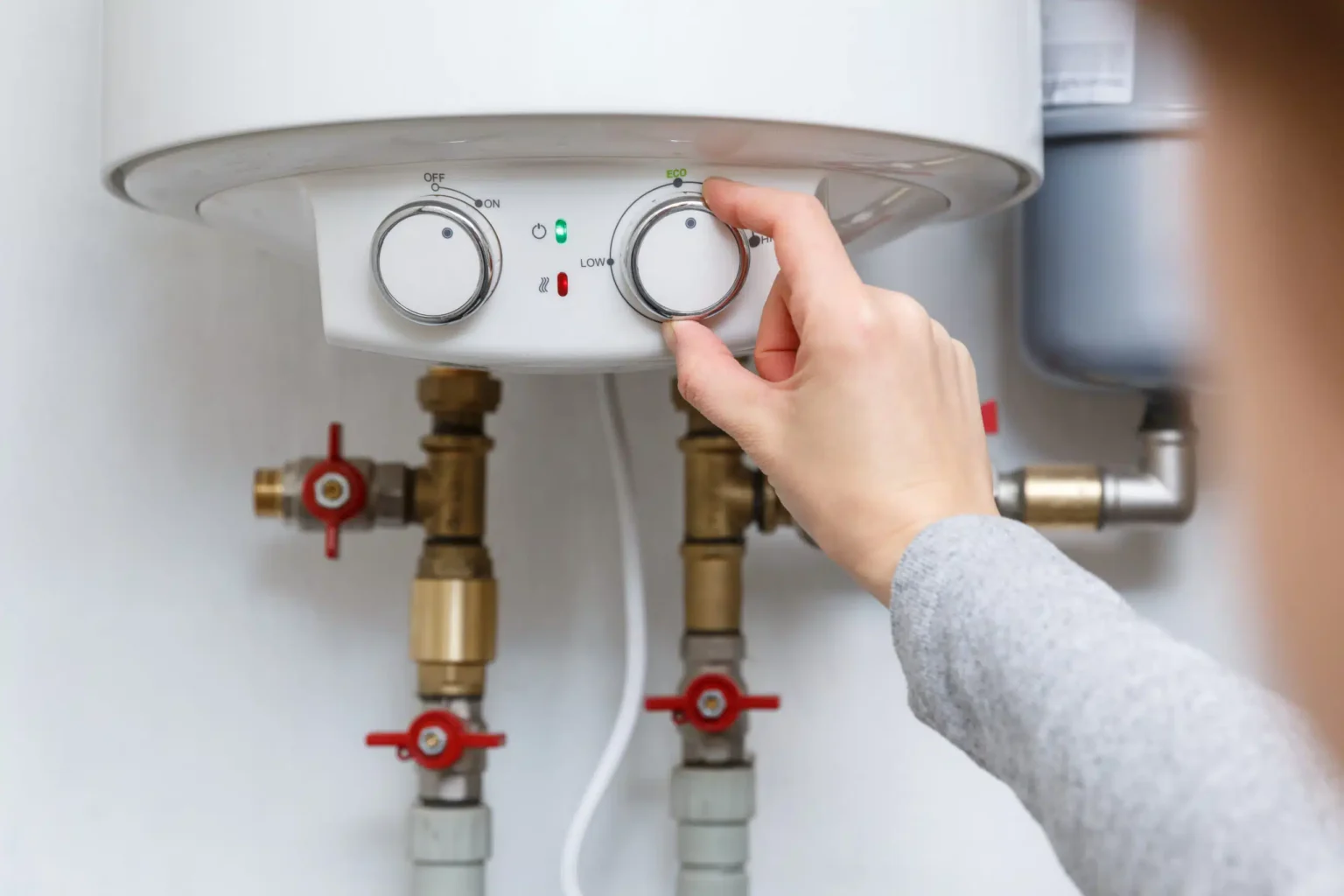 Homeowner adjusting the temperature controls on a water heater in Dunedin